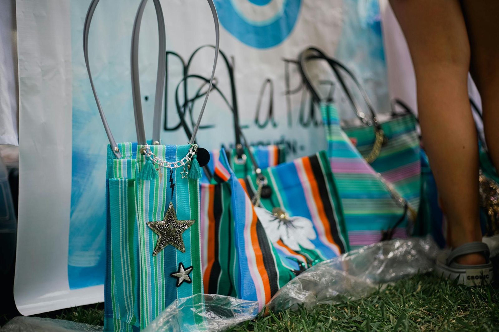 Vibrant striped bags with star charms displayed at an outdoor market.